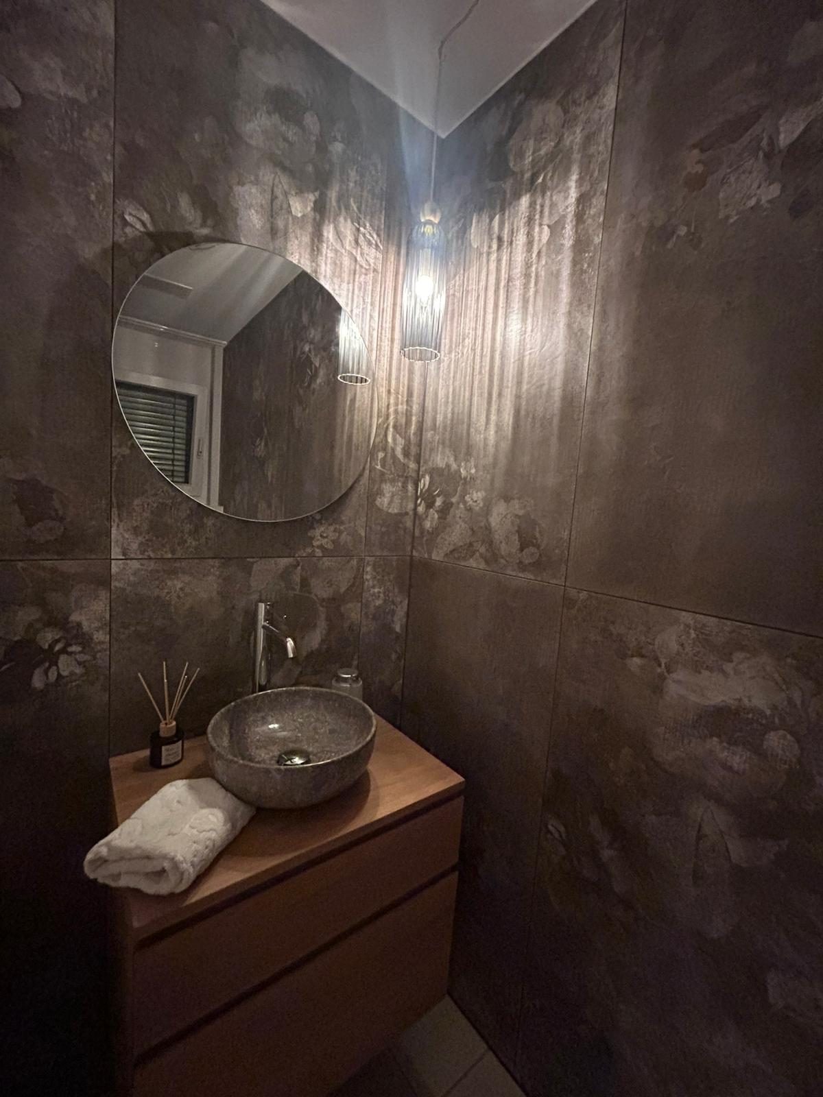 Gäste-WC mit dunklen Wandplatten und Steinwaschbecken