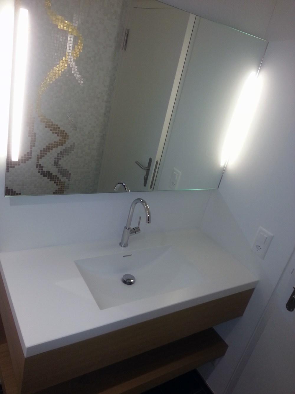 Badezimmer mit Mosaikwand, Waschtisch und Spiegelleuchte